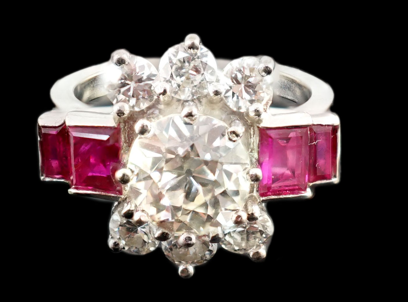 A platinum and single stone diamond dress ring, bordered by six round cut diamond and each shoulder set with two graduated rectangular rubies
